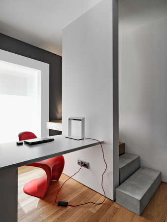 interiors shots of a modern workplace with a modern writing desk near to masonry staircase the floor is made of woodの写真素材