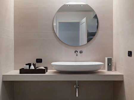 internal shots of a modern bathroom in foreground of counter top washbasin whose walls are coated of pink marbleの写真素材