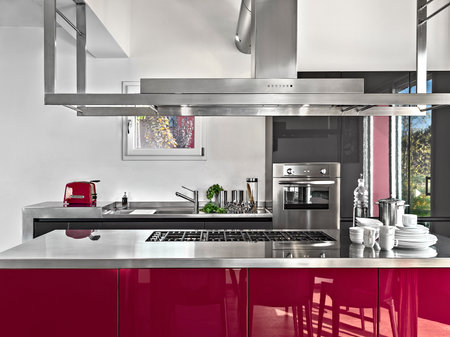 interior of a modern kitchen in the foreground the island kitchen with gas hob and the extractor hood in the background the integrated oven and the sink cabinetの写真素材
