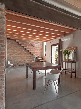 the interior of a dining room that overlooks the entrance with a concrete floor, wooden ceiling and stairs in a rustic villaの写真素材