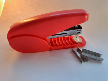 Red stapler and staples on white background. Top view.の写真素材