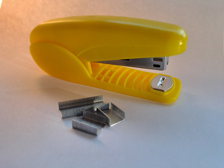 Yellow stapler and staples on a white background, close-up