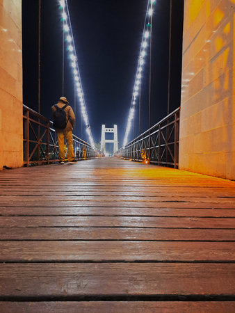 Man walking on a wooden bridge at nightの写真素材