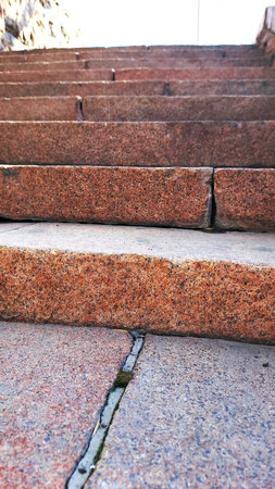Staircase made of red granite slabs close-up.