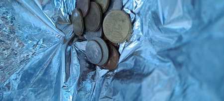 Coins in crumpled aluminium foil as background, closeupの写真素材