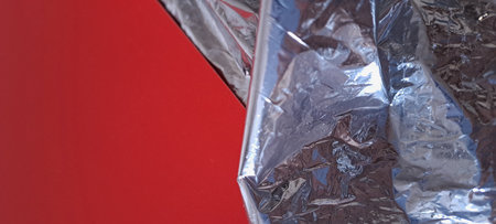 Crumpled aluminum foil on a red background. Close-up.