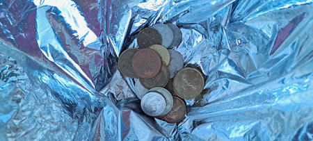 Coins on the background of a crumpled sheet of foilの写真素材