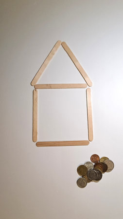 Wooden house and coins on a white background. The concept of real estate and savings.