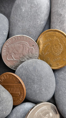 Various coins on grey pebbles background.