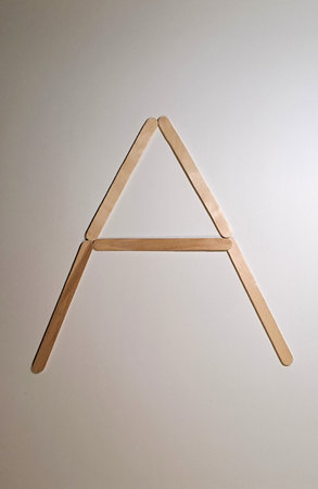 Wooden letter A in the form of a triangle on a white background