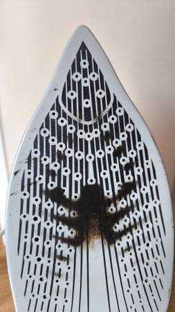 Damage on the bottom of a laundry iron showing carbon deposits and burnt fabric tracesの写真素材
