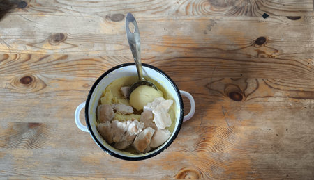 Boiled chicken with mashed potatoes in a bowl on a wooden table