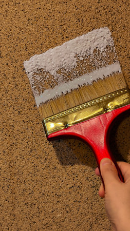 Paint brush with white paint on a brown cork board.の写真素材