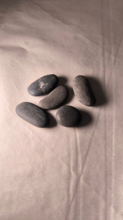 Smooth Dark Stones Group on Textured Paper Surface. Minimalist composition of round gray pebbles...