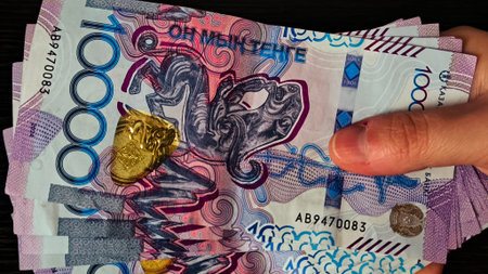 Person Holding a Fan of Tenge Banknotes Close Up. Human hand presenting a spread of high...