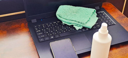 A person applies antibacterial spray to a mobile phone to remove germs and dirt. Maintenance of...