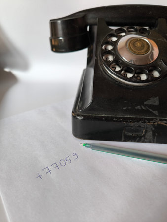 Vintage black rotary telephone with a handwritten number on paper. Classic soviet era dial phone...