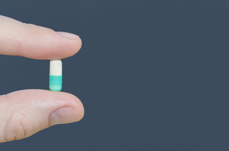 Tablet capsule medicine in fingers close up.の写真素材