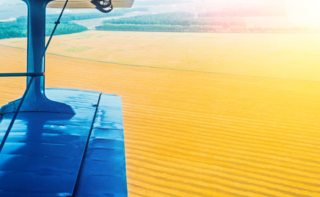 A view of the wing of a turboprop aircraft and a field of corn and wheat in the countryside.の写真素材