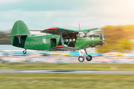 Retro green turbo propeller vintage aircraft flying over the car in the airport.の写真素材