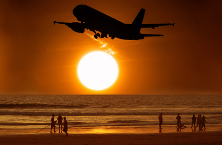 Aircraft take off and the sunset and people on the beach.の写真素材