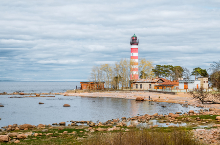 View of the cape on the coast with the old lighthouse in red and white stripesの写真素材
