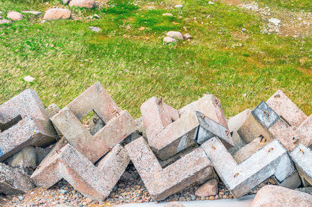 Old concrete protective blocks scattered in the meadow grass and shoreの写真素材