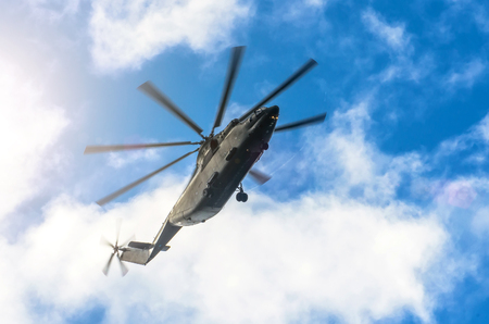 A large transport helicopter is gaining height in the sky clouds of sun, breakdown of steam at the ends of the blades of the propellerの写真素材