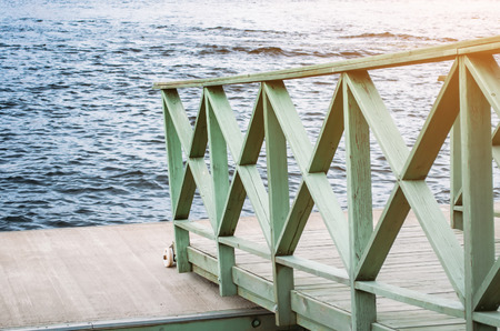 Wooden board on the river pier and the stirring waterの写真素材