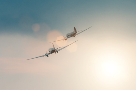 A pair of old turboprop aircraft in the sky at sunset