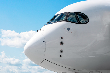 Passenger airplane nose cockpit in blue clouds skyの写真素材