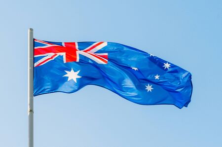 Waving colorful Australia flag on blue skyの写真素材