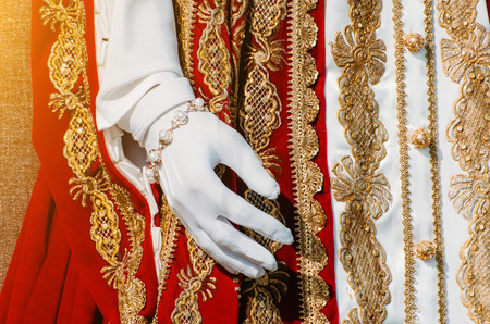 Clothes of a historical imperial woman with red elements, a hand in white glovesの写真素材