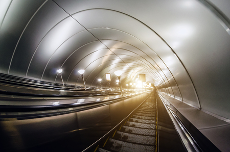 Descent into the tunnel stereo escalator stairs light from belowの写真素材