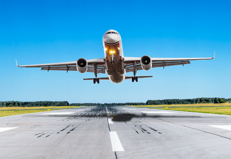 Passenger airplane fly over the runway in good weatherの写真素材