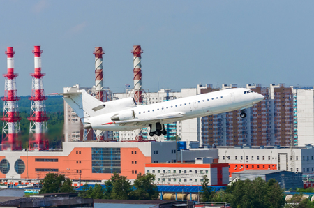 White airplane take off off against the background of the industrial district of the cityの写真素材