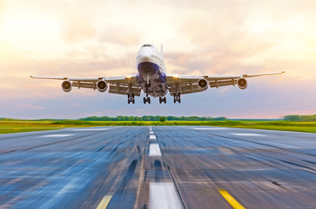 Passenger airplane landing at sunset on a runwayの写真素材