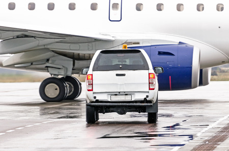 Car is waiting for the airplane to pass along the track at the airportの写真素材