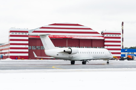 Passenger small plane taxiing to the repair hangar, in winterの写真素材