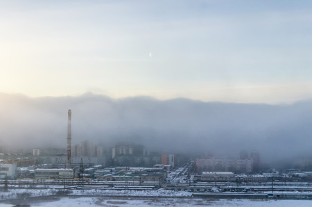 A view of the city shrouded in the morning smog, in the sky the moonの写真素材