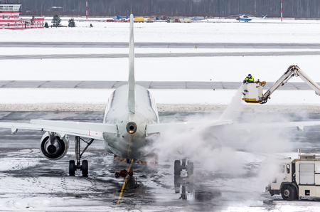 Ground crew provides de-icing. They are spraying the aircraft, which prevents the occurrence of frostの写真素材