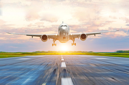 Passenger airplane landing at sunset on a runwayの写真素材