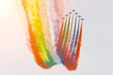 Group of white turboprop airplane with a trace of smoke against a blue skyの写真素材