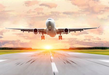 Passenger airplane landing at sunset on a runway