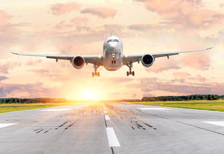 Passenger airplane landing at sunset on a runwayの写真素材