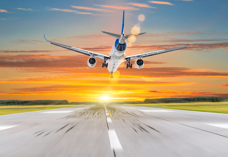 Passenger airplane landing at sunset on a runwayの写真素材