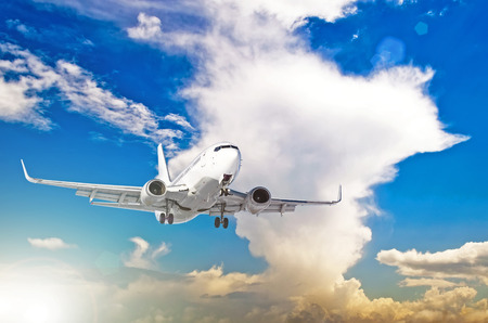 Airplane at fly on the sky with cumulus clouds sunsetの写真素材