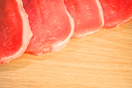 Pieces of meat pork chopped on a table board with a wooden textureの写真素材