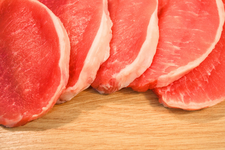 Pieces of meat pork chopped on a table board with a wooden textureの写真素材