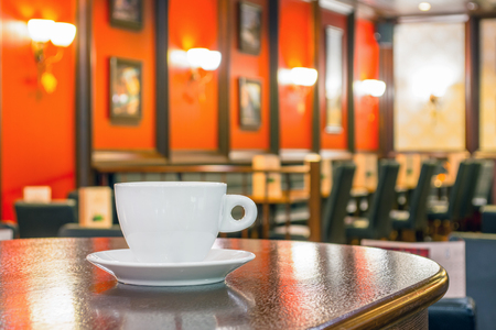 White cup of coffee on a wooden table in a cafeの写真素材